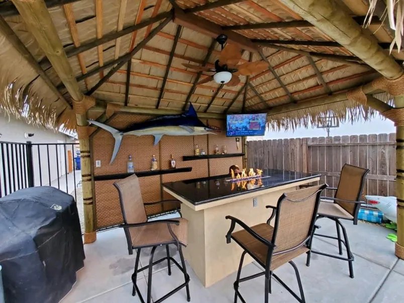Inside a palapa tiki bar with bar stools and a mounted marlin